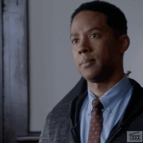 A Man In A Suit And Tie Is Standing In Front Of A Clapper Board That Says ' Movie Maker ' On It GIF