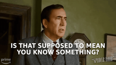 A Man In A Suit And Tie Is Standing In Front Of A Clock And Asking " Is That Supposed To Mean You Know Something " GIF