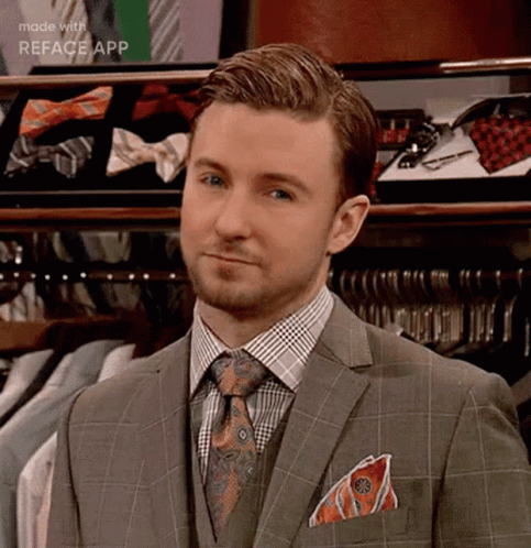 A Man In A Suit And Tie Is Standing In Front Of A Closet Filled With Shirts And Ties . GIF