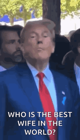 A Man In A Suit And Tie Is Standing In Front Of A Crowd And Says `` Who Is The Best Wife In The World ? '' GIF