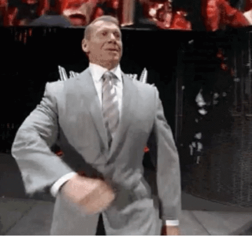 A Man In A Suit And Tie Is Standing In Front Of A Crowd . GIF