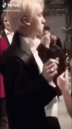 A Man In A Suit And Tie Is Standing In Front Of A Crowd . GIF
