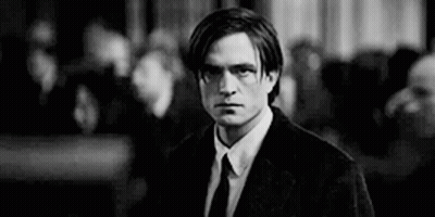 A Man In A Suit And Tie Is Standing In Front Of A Crowd . GIF