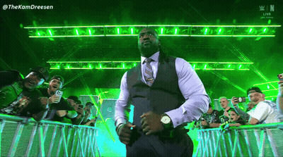 A Man In A Suit And Tie Is Standing In Front Of A Crowd With The Letters N On The Bottom Right GIF