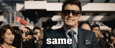 A Man In A Suit And Tie Is Standing In Front Of A Crowd With The Word Same Written On The Screen . GIF