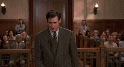 A Man In A Suit And Tie Is Standing In Front Of A Crowd GIF