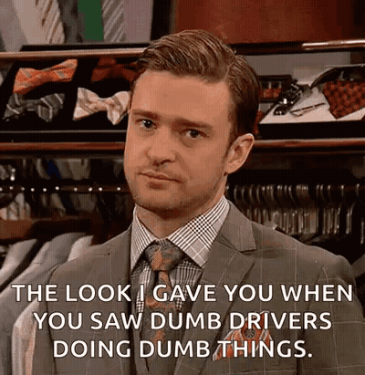 A Man In A Suit And Tie Is Standing In Front Of A Display Of Ties And Shirts . GIF