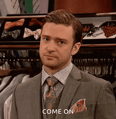 A Man In A Suit And Tie Is Standing In Front Of A Display Of Ties And Shirts . GIF