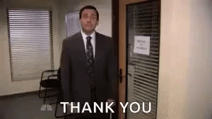 A Man In A Suit And Tie Is Standing In Front Of A Door And Saying Thank You . GIF