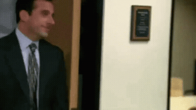 A Man In A Suit And Tie Is Standing In Front Of A Door In An Office . GIF