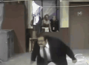 A Man In A Suit And Tie Is Standing In Front Of A Door That Says 14 GIF