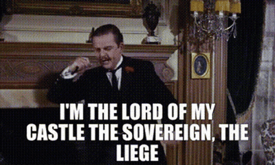 A Man In A Suit And Tie Is Standing In Front Of A Fireplace And Talking On A Phone . GIF