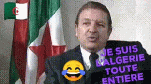A Man In A Suit And Tie Is Standing In Front Of A Flag With A Laughing Smiley Face . GIF