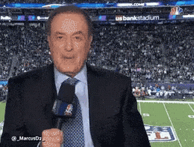 A Man In A Suit And Tie Is Standing In Front Of A Football Field GIF