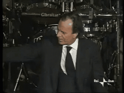 A Man In A Suit And Tie Is Standing In Front Of A Gibraltar Drum GIF