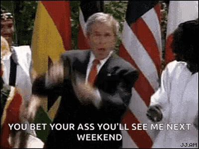 A Man In A Suit And Tie Is Standing In Front Of A Group Of Flags . GIF