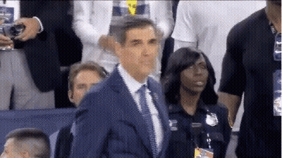 A Man In A Suit And Tie Is Standing In Front Of A Group Of People . GIF