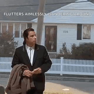A Man In A Suit And Tie Is Standing In Front Of A House Holding A Jacket . GIF