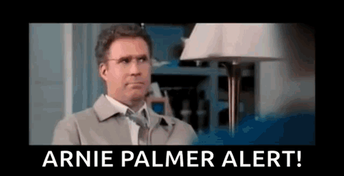 A Man In A Suit And Tie Is Standing In Front Of A Lamp And A Sign That Says `` Arnie Palmer Alert '' . GIF