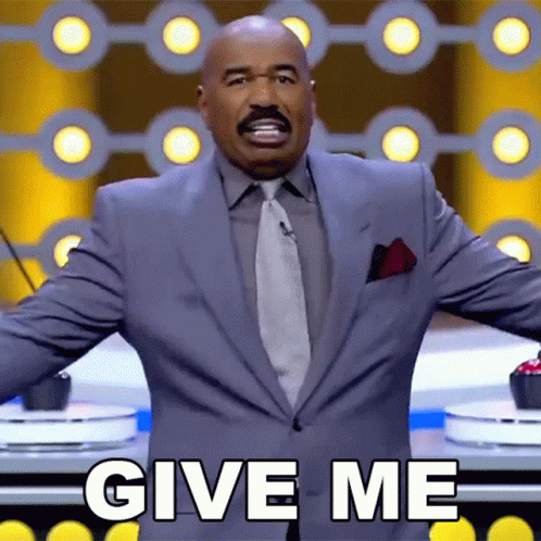 A Man In A Suit And Tie Is Standing In Front Of A Microphone And Says Give Me GIF