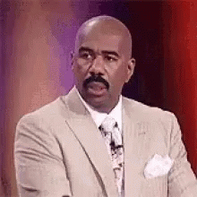 A Man In A Suit And Tie Is Standing In Front Of A Microphone . GIF