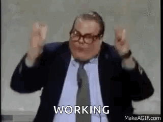 A Man In A Suit And Tie Is Standing In Front Of A Microphone With His Arms In The Air . GIF