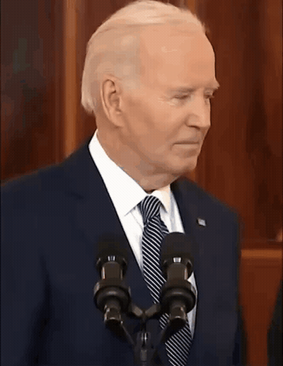 A Man In A Suit And Tie Is Standing In Front Of A Microphone With The Words Is That A Joke Written Below Him GIF