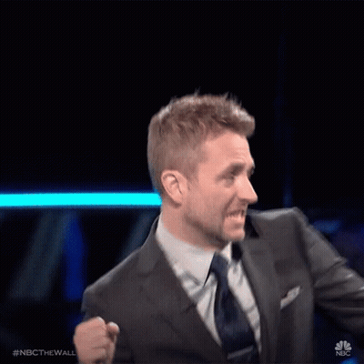 A Man In A Suit And Tie Is Standing In Front Of A Nbc Sign GIF