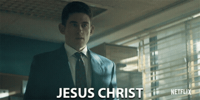 A Man In A Suit And Tie Is Standing In Front Of A Netflix Logo GIF