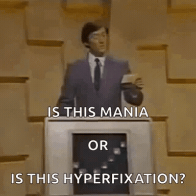A Man In A Suit And Tie Is Standing In Front Of A Podium And Asking Is This Mania Or Is This Hyperfixation ? GIF
