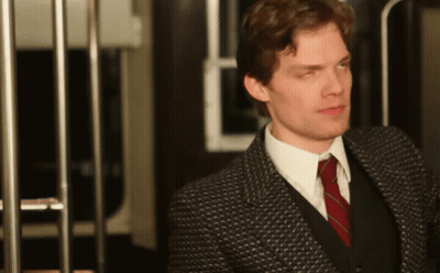 A Man In A Suit And Tie Is Standing In Front Of A Railing GIF