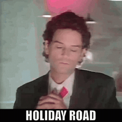 A Man In A Suit And Tie Is Standing In Front Of A Red Light . GIF