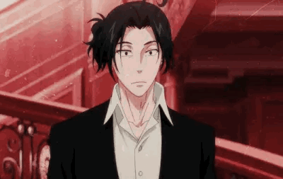 A Man In A Suit And Tie Is Standing In Front Of A Red Wall . GIF