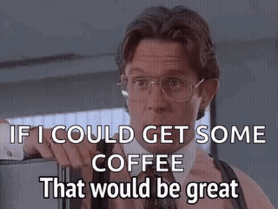 A Man In A Suit And Tie Is Standing In Front Of A Refrigerator And Talking About Coffee . GIF