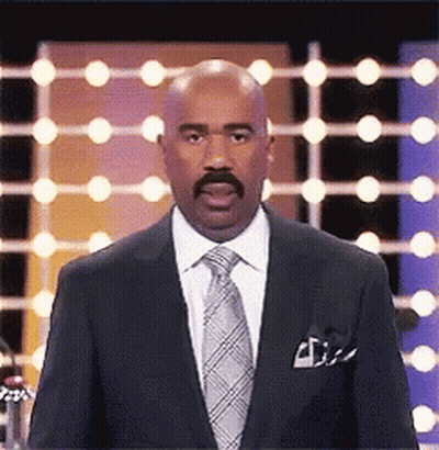 A Man In A Suit And Tie Is Standing In Front Of A Row Of Lights . GIF