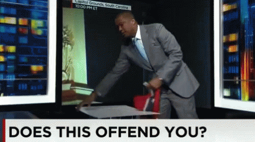 A Man In A Suit And Tie Is Standing In Front Of A Screen That Says Does This Offend You GIF