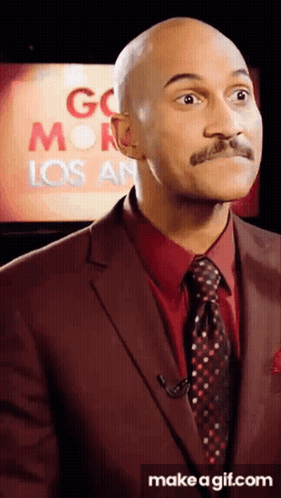 A Man In A Suit And Tie Is Standing In Front Of A Screen That Says Go Monday Los Angeles GIF