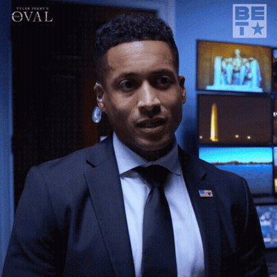 A Man In A Suit And Tie Is Standing In Front Of A Screen That Says Oval GIF