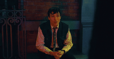 A Man In A Suit And Tie Is Standing In Front Of A Sign That Says ' A ' GIF