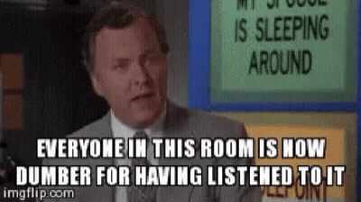 A Man In A Suit And Tie Is Standing In Front Of A Sign That Says Everyone In This Room GIF