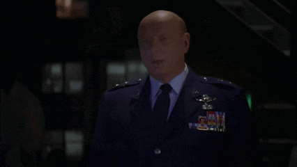 A Man In A Suit And Tie Is Standing In Front Of A Sign That Says Godspeed GIF