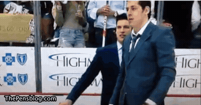 A Man In A Suit And Tie Is Standing In Front Of A Sign That Says Highway . GIF
