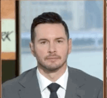 A Man In A Suit And Tie Is Standing In Front Of A Sign That Says Pk GIF