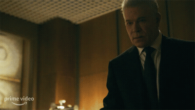 A Man In A Suit And Tie Is Standing In Front Of A Sign That Says Prime Video On It GIF