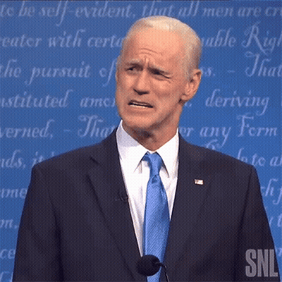 A Man In A Suit And Tie Is Standing In Front Of A Snl Sign GIF