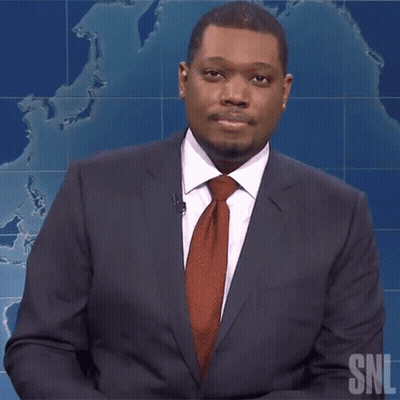 A Man In A Suit And Tie Is Standing In Front Of A Snl Sign GIF