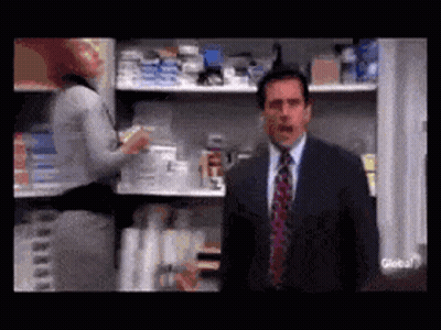 A Man In A Suit And Tie Is Standing In Front Of A Store Shelf . GIF