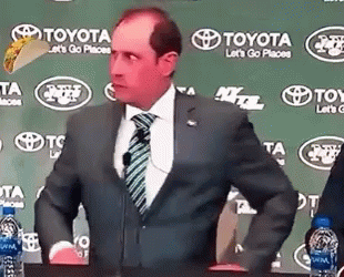 A Man In A Suit And Tie Is Standing In Front Of A Toyota Sign . GIF
