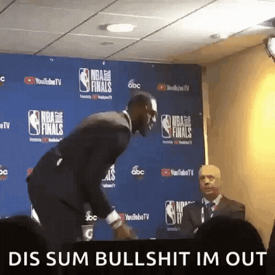 A Man In A Suit And Tie Is Standing In Front Of A Wall That Says Nba Finals GIF