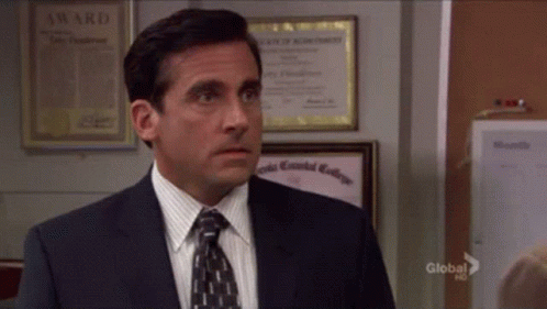 A Man In A Suit And Tie Is Standing In Front Of A Wall With A Certificate That Says Award On It GIF